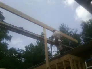 Carpenter setting a ridge beam over a new addition frame — Ice Dam Removal by Roofing Brothers in Benzonia