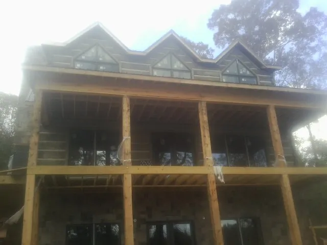 Dormers and porch framing on a large log home under construction — Roof Coating work by our crew in Benzonia