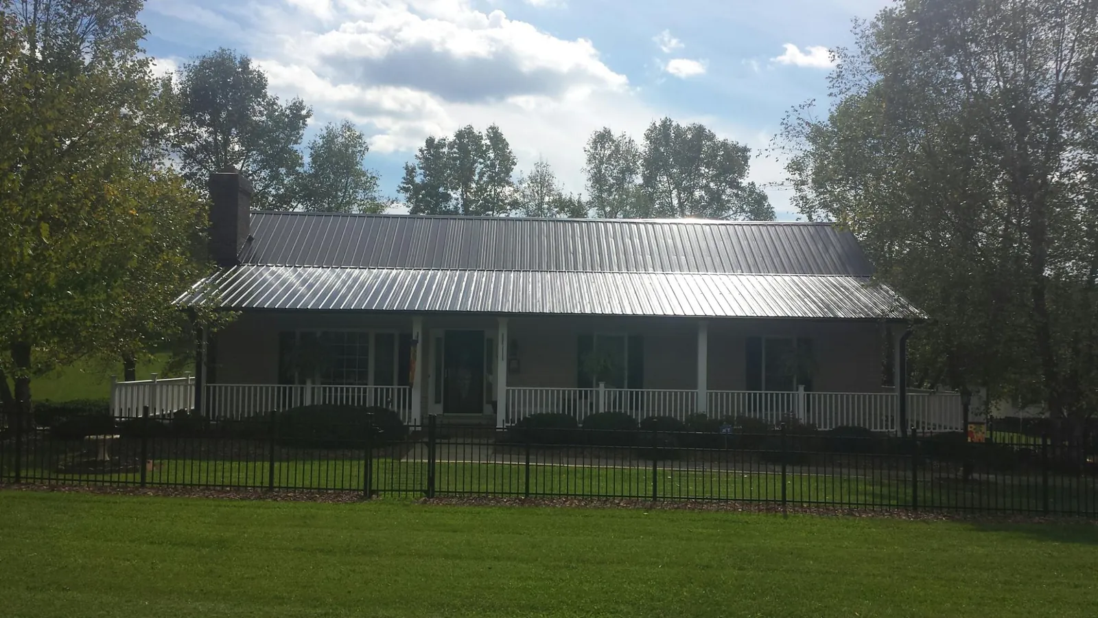 Gray metal roof on a brick ranch with a full width front porch — Gutter Guard Installation work by our crew in Benzonia