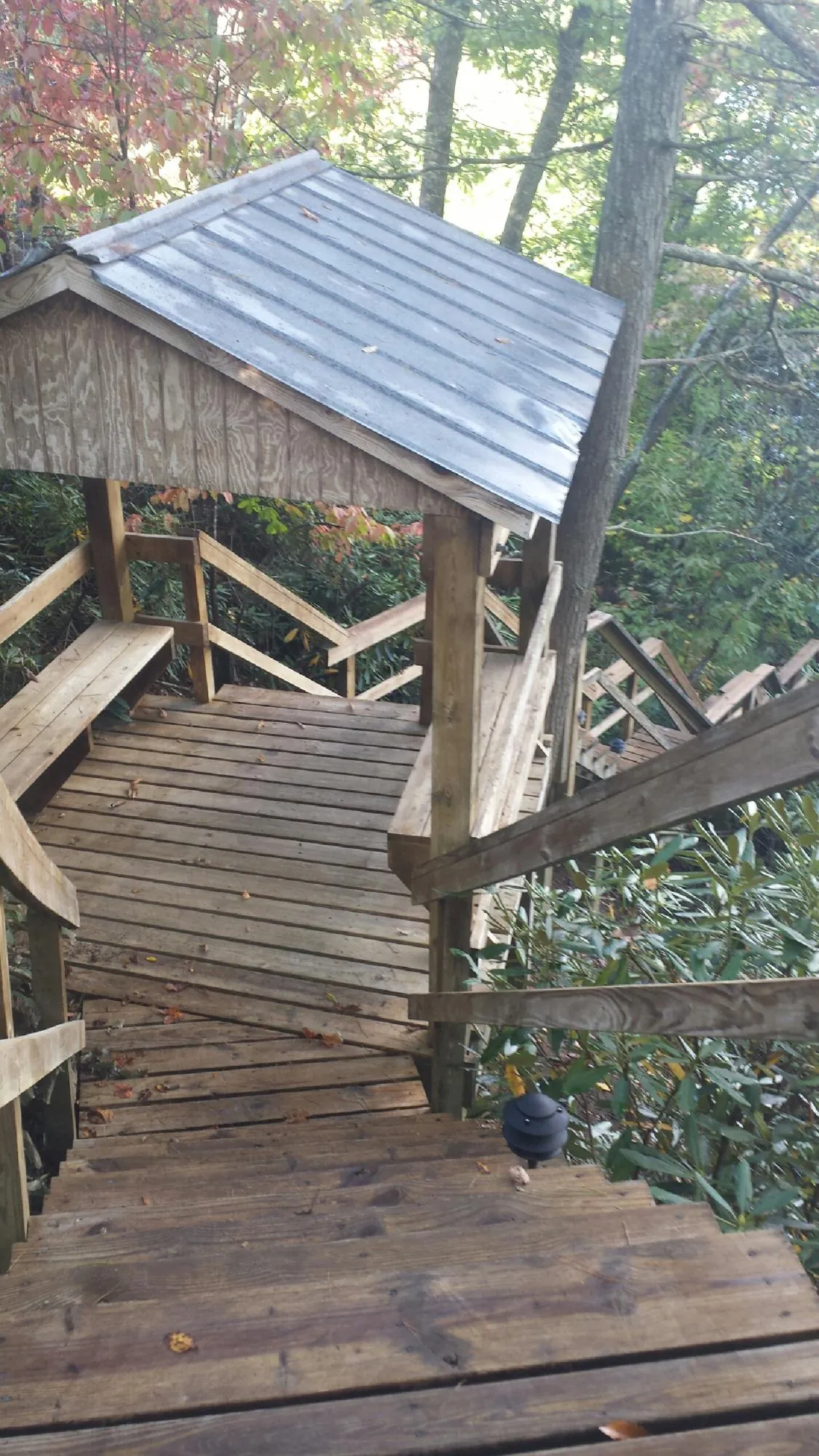 Metal roofed shelter over wooden steps on a wooded walkway — Skylight Repair & Installation work by our crew in Benzonia