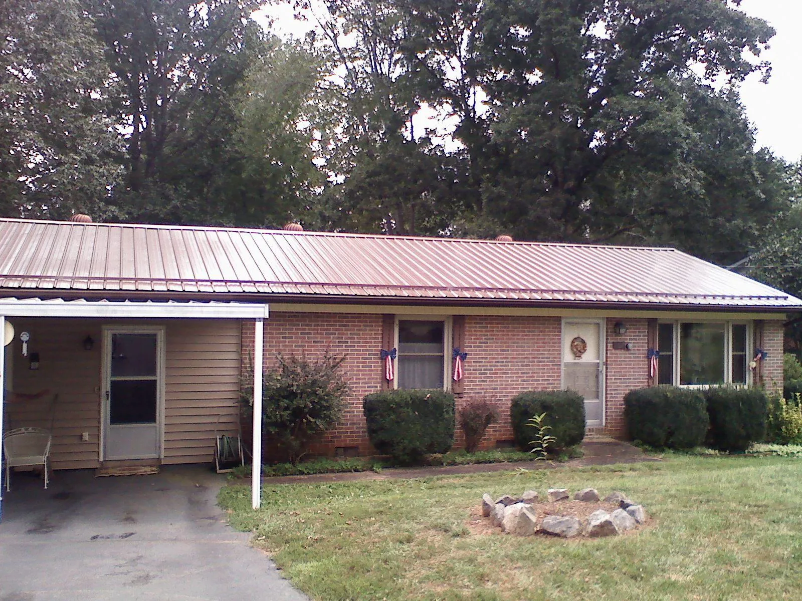 Bronze metal roof and carport on a brick ranch home — Roof Repair work by our crew in Benzonia