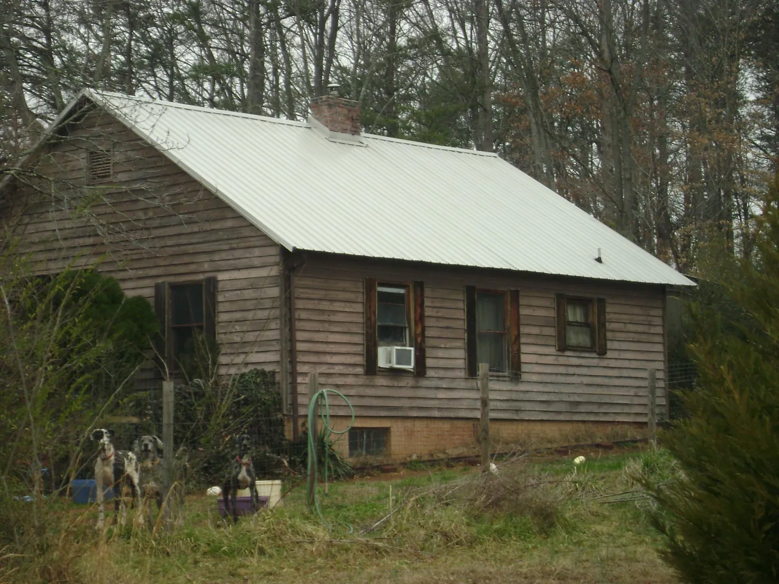White metal roof on an old wood sided farmhouse, from a Metal Roof Installation job in Benzonia